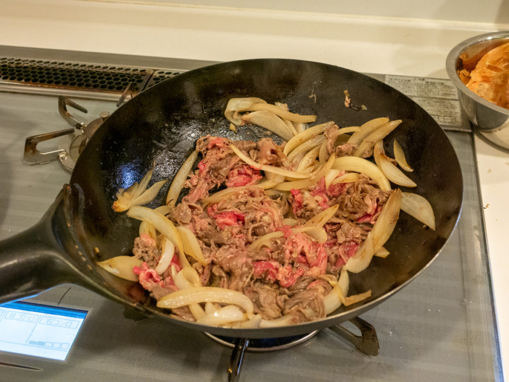 中華鍋で肉と玉ネギを炒めているところ